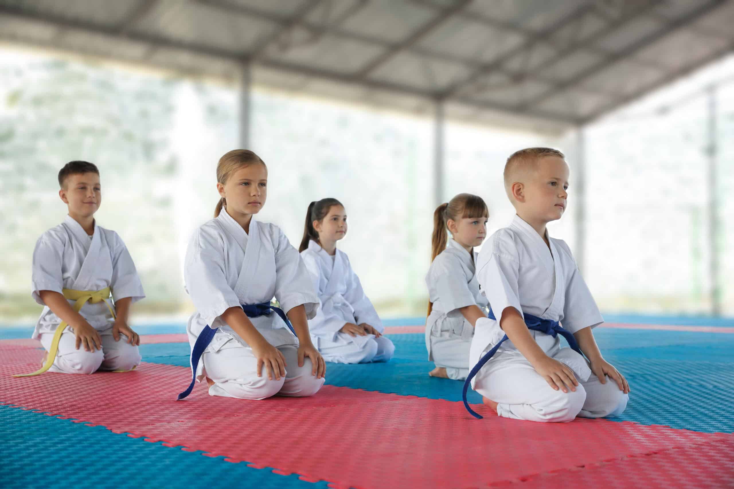 Jeunes judokas en formation, assis en position de méditation sur le tatami.